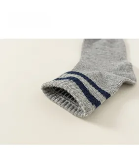 Detail close-up of light grey cotton socks with navy blue stripes on ribbed cuffs