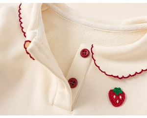 Close-up of cream children's fleece top with red wavy collar and strawberry embroidery