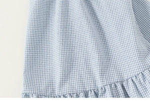 Detail of blue and white gingham cotton fabric with ruffled hem on child's summer dress