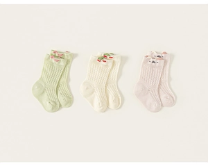 Détail de trois paires de chaussettes en maille pour bébé avec nœud, cerise et oreilles d'animaux