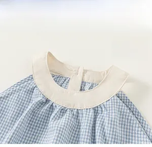 Close-up of baby dress neck detail with blue plaid pattern and cream round collar