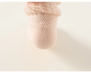 Gros plan sur une chaussette bébé rose pâle avec maille respirante et revers élastique