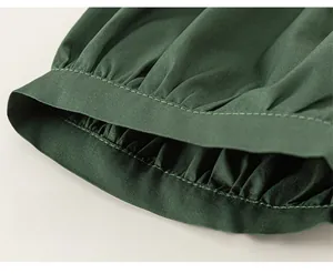 Détail du tissu vert foncé montrant les coutures haute densité et le design plissé du poignet