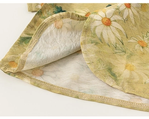 Gros plan sur l'imprimé marguerite et coutures soignées sur tissu en lin jaune