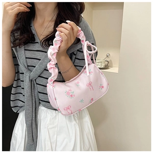 Close-up of floral shoulder bag with pink roses, bow prints, and pleated cloud handle