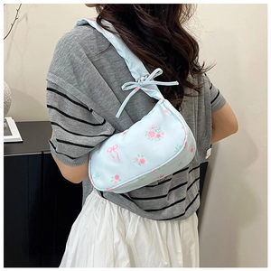 Detail of light blue floral shoulder bag with pink rose patterns and bow knot strap