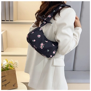 Close-up of floral nylon shoulder bag with pink roses and bow prints on a black base