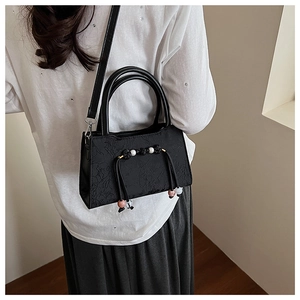 Detail of black jacquard handbag with traditional knots, pearls and beads on model