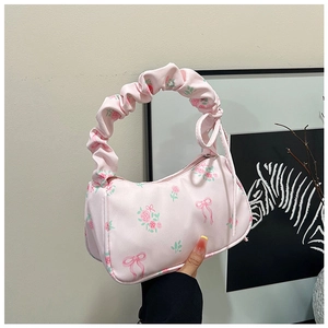 Detail of light pink floral shoulder bag with ruched handle and rose bow pattern