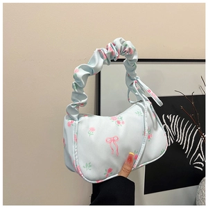 Close-up of light blue floral print handbag featuring ruffled handles and bow patterns