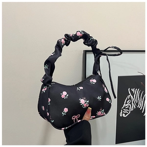Detailed view of the black satin floral bag with scrunchie handle and pink rose patterns