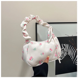 Detail of floral underarm bag featuring pink rose print and ruffled scrunchie handle