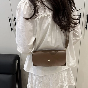 Brown crocodile pattern crossbody bag with vintage gold buckle and woven strap on model