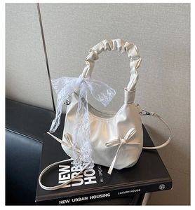 Détail du sac à main blanc plissé en cuir avec des rubans de dentelle et des nœuds