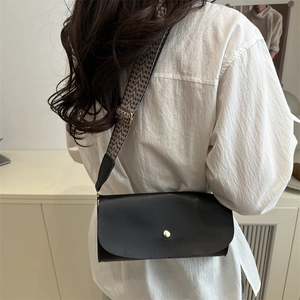 Modern black faux leather crossbody bag with patterned strap and golden stud closure