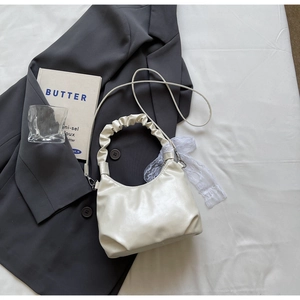 Détail du sac à main plissé blanc crème avec ruban en dentelle et bandoulière amovible