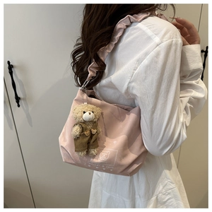 Detail of pink canvas tote with ruffled strap and cute plush bear charm on female model
