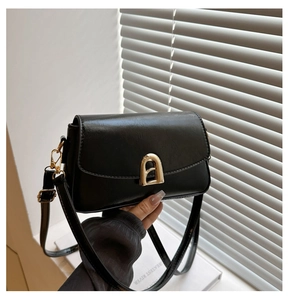 Close-up of black PU leather handbag with golden magnetic saddle buckle and adjustable strap
