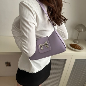 Chic purple underarm baguette bag with silver metal bow worn by model in a stylish interior
