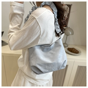 Detail of light blue pleated shoulder bag featuring ruffle strap and bear logo patch