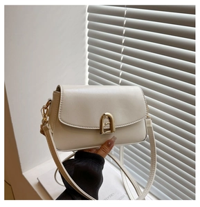 Close-up of cream textured PU leather bag with elegant gold arch clasp detail