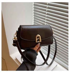 Detailed view of dark brown glossy leather bag featuring elegant gold arched metal lock