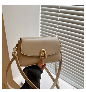 Close-up of beige leather crossbody bag featuring an elegant gold D-ring buckle