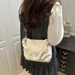 Minimalist cream shoulder bag featuring elegant ruffled straps and a cute fabric label