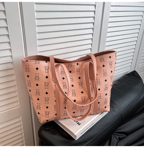 Détail d'un sac cabas rose en similicuir avec motif ours sur un livre et un canapé