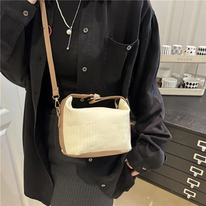 Vertical striped cream crossbody bag with brown leather trim and gold buckle shown on model