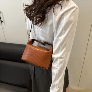 Caramel and brown textured pleated crossbody bag with slim strap shown on model