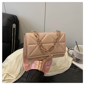 Detailed close-up of pink quilted crossbody bag with wide artistic strap and chain handle