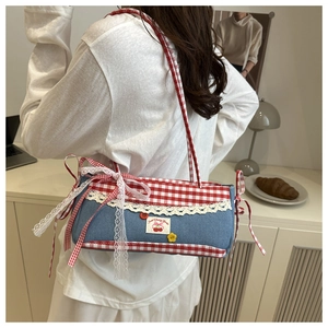 Detail of denim armpit bag featuring red gingham trim and white lace ruffles decoration