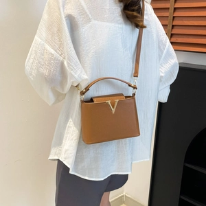 Elegant brown leather trapezoid handbag with gold V-shaped metal buckle for women