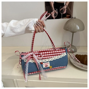 Detail of denim handbag with red plaid trim, lace edges and large bow accent