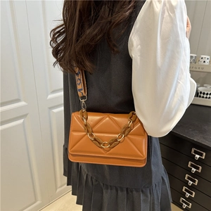Brown quilted crossbody bag with amber chain and wide patterned strap in fashion indoor set