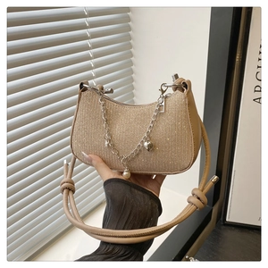 Close-up detail of stylish glitter shoulder bag with metallic chain and pearl pendant.