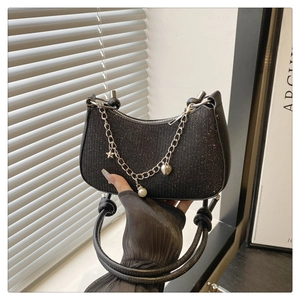Detailed view of the black sparkling underarm bag with chain and pearl pendant.