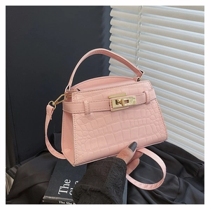 Detail of pink crocodile pattern handbag featuring a gold turn-lock closure and leather strap