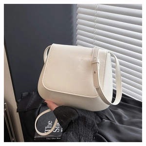 Detailed macro view of the smooth cream-colored faux leather texture and elegant bag flap