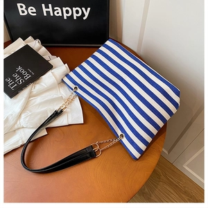 Close-up of blue and white striped tote bag with gold chain and black leather strap