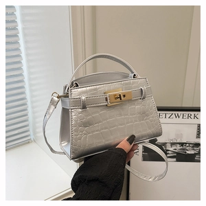 Detailed close-up of silver crocodile embossed handbag with golden metallic lock and handle