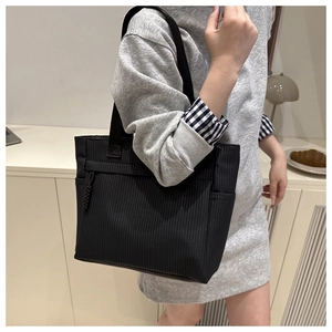 Détail du sac cabas en velours côtelé noir avec texture verticale et poche zippée latérale
