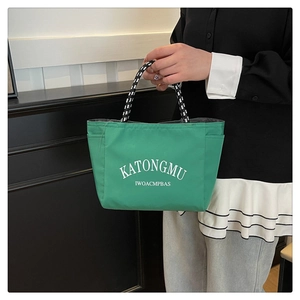 Detail of green nylon tote bag with woven rope handles and white letter printing
