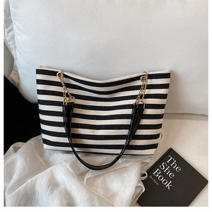 Close-up of black and white striped canvas tote bag with gold metal chain strap