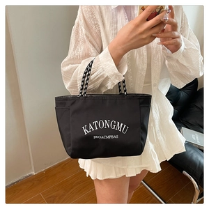 Detail view of the black tote bag with white lettering and polka dot rope handles