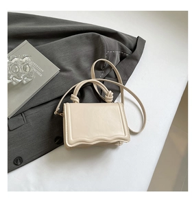 Detail view of cream PU leather shoulder bag featuring wavy edge and knotted handle detail