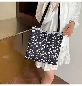 Detail of black floral tote bag with delicate white lace trim and canvas straps