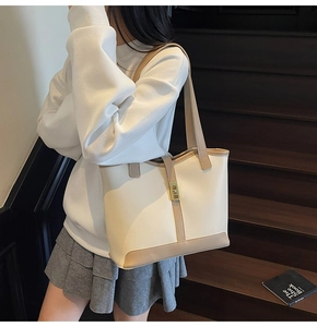 Detail view of contrast color tote bag with vintage gold twist lock on beige leather