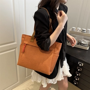 Grand sac fourre-tout tissé orange-brun avec une large bandoulière dans un cadre chic